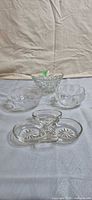 Four clear pressed-glass pieces on table: three bowls, one divided dish