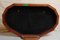 Front of octagonal wooden display with black velvet and two brass pins