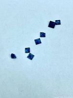 Seven square blue sapphires arranged on white background