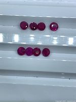 Eight loose round rubies displayed in two rows