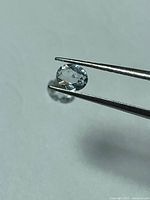 Gemstone held in tweezers showing clarity and cut