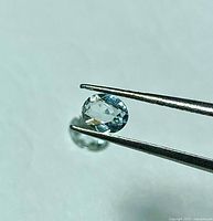 Close-up of single faceted aquamarine held by tweezers