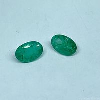 Two loose oval emeralds on white background