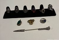 Full lot showing seven rings on display, two pendants, silver ring, hatpin