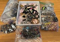 Overview of all bags and open box containing assorted costume jewelry and findings