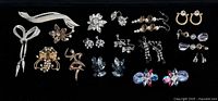 Full lot overview showing brooches and earrings on black background
