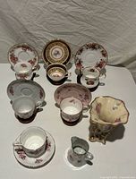 Full group view of five teacups, six saucers, vase and creamer