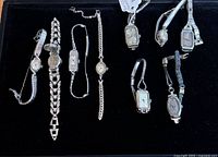 Nine vintage ladies watches laid out on black background