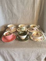 All six teacup and saucer sets grouped on draped fabric