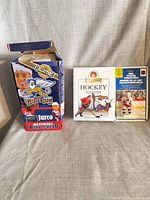 Front view of all three items: bobblehead box, card game, figure blister