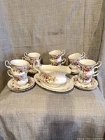 Six footed cups, six saucers, gravy boat on oval plate displayed
