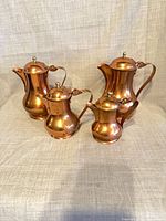 Front view of four matching copper vessels with lids