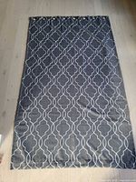 Single grey geometric curtain panel laid flat showing pattern and grommets