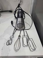 Mixer standing upright with cord and four attachments displayed