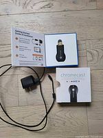 Chromecast dongle, cable, power adapter, box, and setup guide displayed on floor