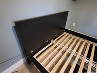 Headboard and side rail of black IKEA Malm bed frame showing finish and slat support holes