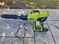 Leaf blower with two batteries and charger displayed on patio