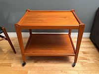 angled view of teak bar cart showing two tiers and casters