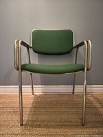 Front view of armchair showing tubular steel frame and green upholstery