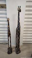 Front view of both wooden giraffes standing side by side