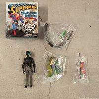 Boxed Superman figure, sealed accessory bag, loose black figure, bagged Riddler and red/white figure