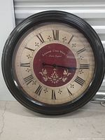 Front view of round wall clock showing entire face, frame, numerals and branding