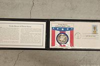 Open display folder showing information card and first-day cover with coin