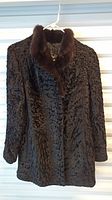 Front view of textured dark fur coat on hanger