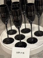 Front view of all seven black glass champagne flutes on tray