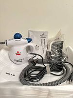 Full view of steamer, hose, attachments bag, manual