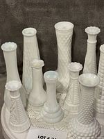 Group shot of all 10 white milk glass vases on round table