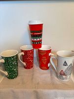Group shot of four ceramic mugs and one plastic travel cup