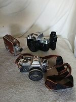 Group shot of three film cameras: Nikon SLR, Ultima 35mm, brown 8mm movie camera