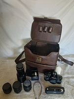 Entire lot laid out: Canon camera body, four lenses, motor drive, strap and brown carry case