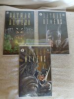 Three bagged Batman/Aliens comics displayed on surface