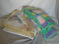 Both quilts folded together showing butterfly quilt and pastel crocheted afghan