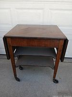 Cart with both leaves folded showing compact form, shelves and casters visible