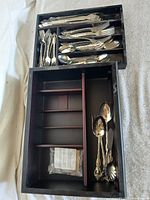 Overall view of flatware set in open two-tier case showing multiple utensils