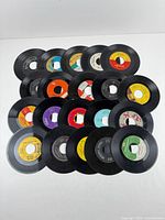 All twenty unsleeved 7-inch 45 RPM records laid out
