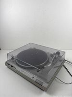 Turntable with dust cover closed, power and audio cables visible