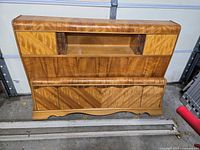 Front view of veneered bookcase headboard with open shelf and chevron footboard leaning below