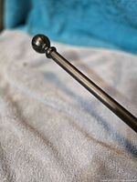 Close-up of metal curtain rod showing finial and finish