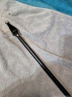 Close-up of black metal curtain rod showing spear-style finial and telescoping shaft