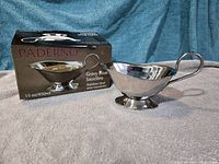 Gravy boat positioned beside its retail box showing capacity marking 15 oz⁄450 ml and Paderno branding.