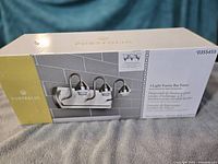 Boxed Portfolio 3-light vanity bar fixture showing branding, model number and product image