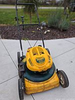 Front view of yellow and green Yard-Man 6 hp gas push lawnmower with folding handle