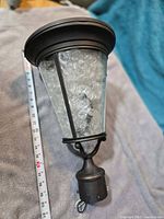 Full view of Kichler outdoor post light showing seeded glass and bronze frame with measuring tape for scale