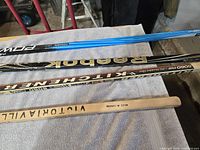 Four hockey stick shafts showing brands Reebok, Victoriaville and others