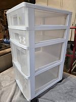 Front angled view of white plastic four-drawer storage cart on wheels