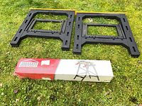 Two black plastic sawhorses and boxed Jobmate folding workbench on grass